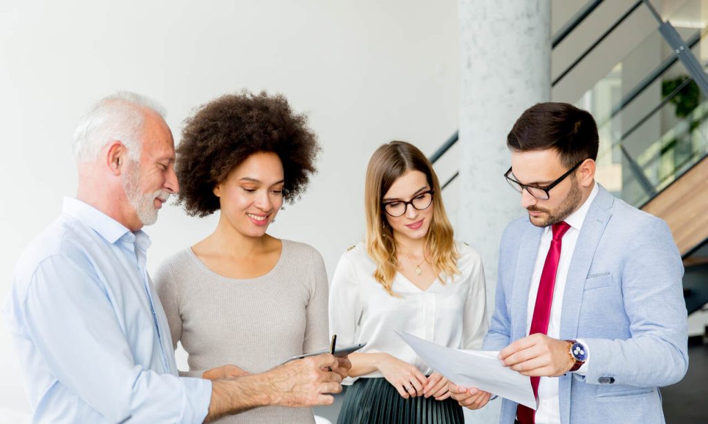 Profissionais avaliando seguro de vida em grupo em contrato impresso e com um tablet nas mãos.