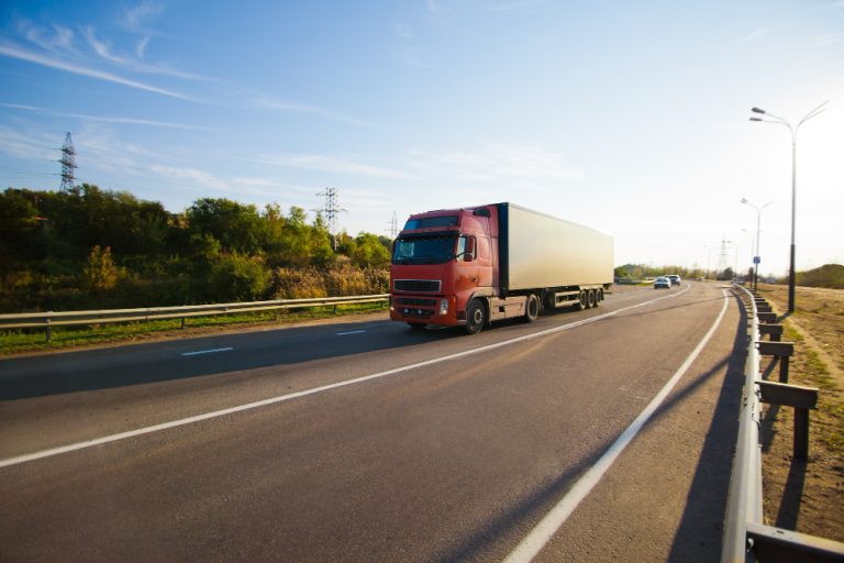 Caminhão transportando carga em rodovia brasileira sob monitoramento de segurança com seguro de carga roubo