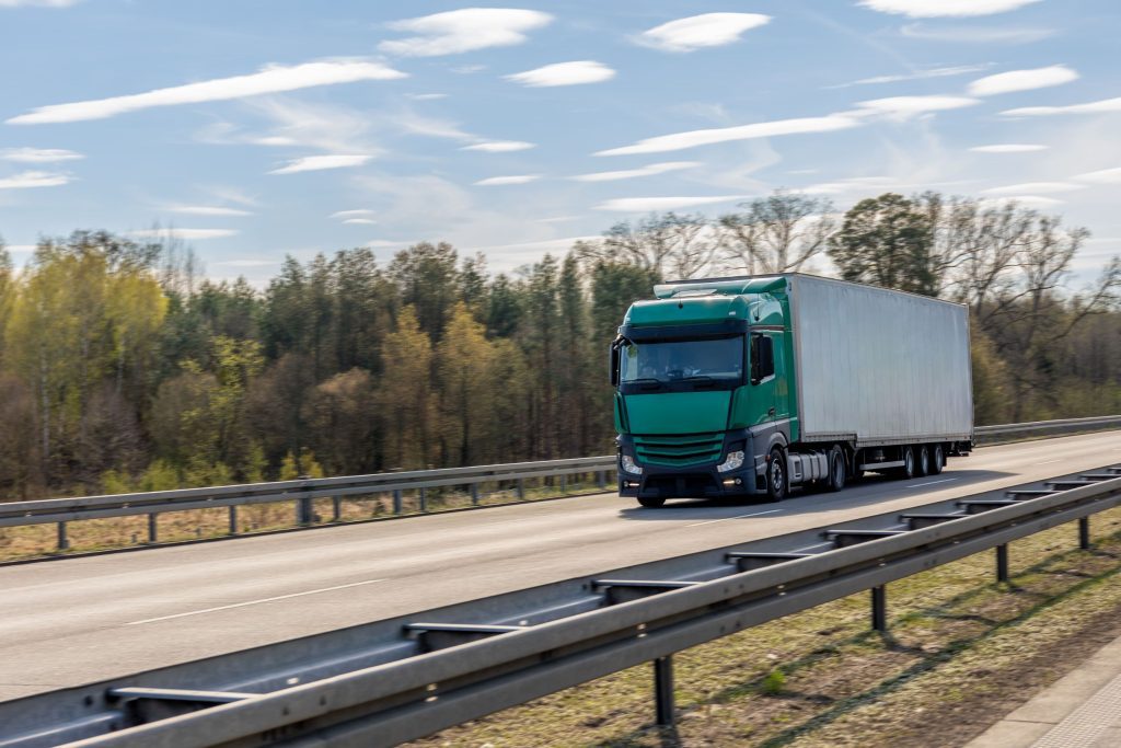 Caminhão de carga transitando em rodovia ladeada por áreas de preservação ambiental.